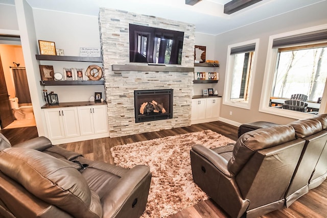 living room featuring a stone fireplace, dark hardwood / wood-style flooring, and crown molding