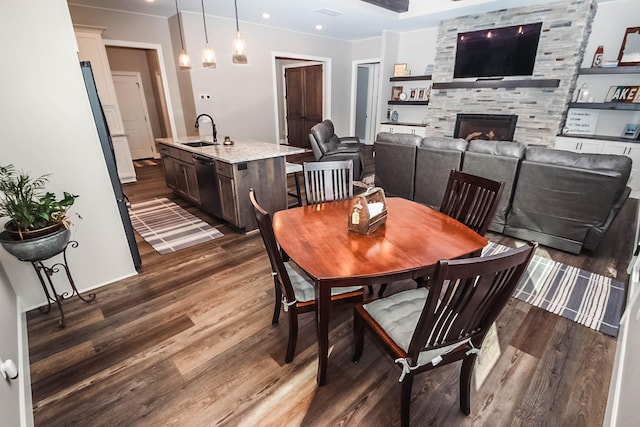 dining area with dark hardwood / wood-style floors, a fireplace, crown molding, and sink