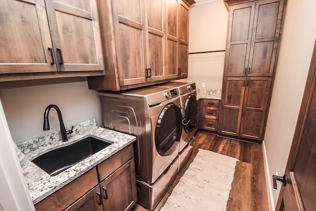 laundry room with cabinets, washing machine and dryer, dark hardwood / wood-style floors, and sink