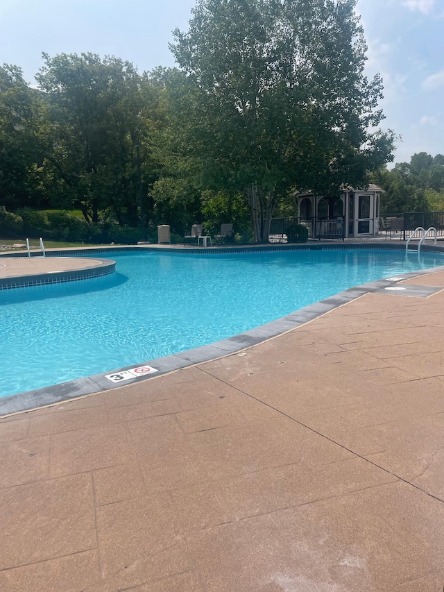 community pool with a patio area and fence