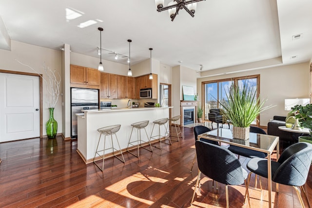 interior space with dark wood-style floors, refrigerator, brown cabinets, stainless steel microwave, and visible vents