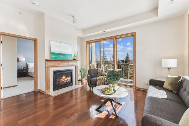 living room featuring visible vents, a fireplace, baseboards, and hardwood / wood-style flooring