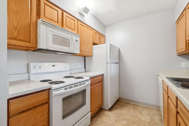 kitchen featuring a textured ceiling, sink, and white appliances