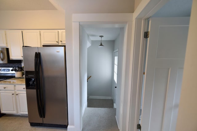 kitchen with appliances with stainless steel finishes, decorative light fixtures, white cabinetry, tasteful backsplash, and light tile patterned floors