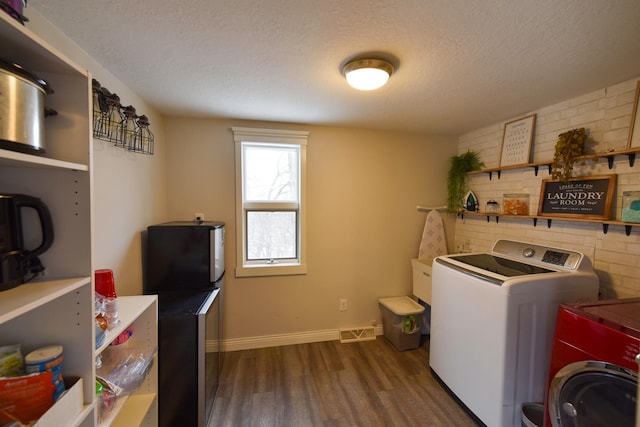 washroom featuring a textured ceiling, dark hardwood / wood-style floors, and washing machine and dryer