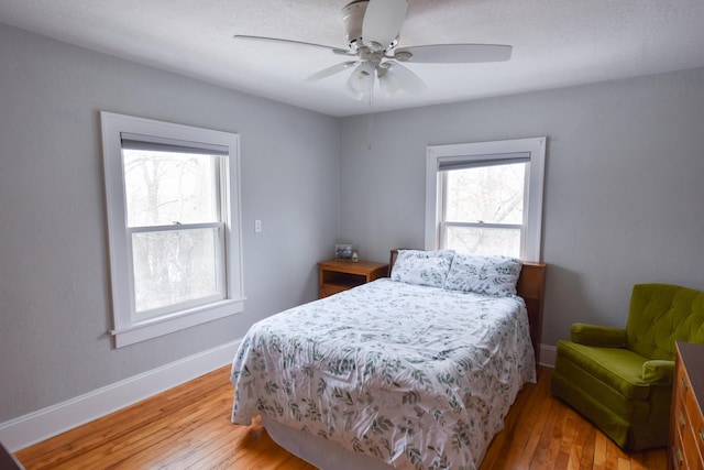 bedroom featuring ceiling fan, multiple windows, and hardwood / wood-style flooring