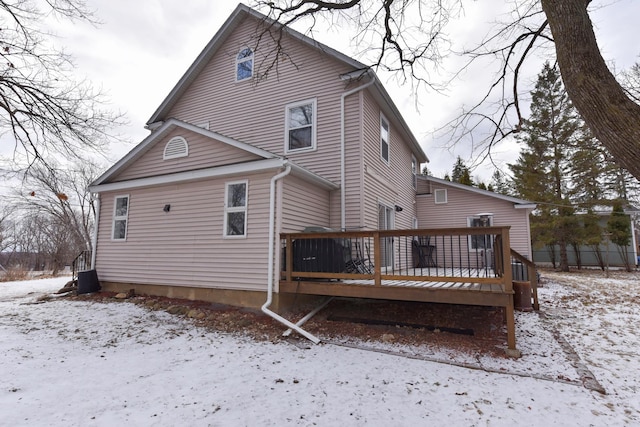 snow covered rear of property with a deck