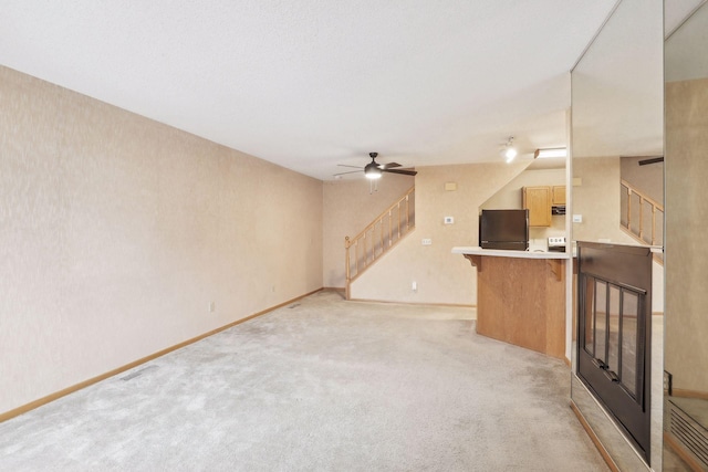 unfurnished living room featuring light colored carpet, vaulted ceiling, and ceiling fan