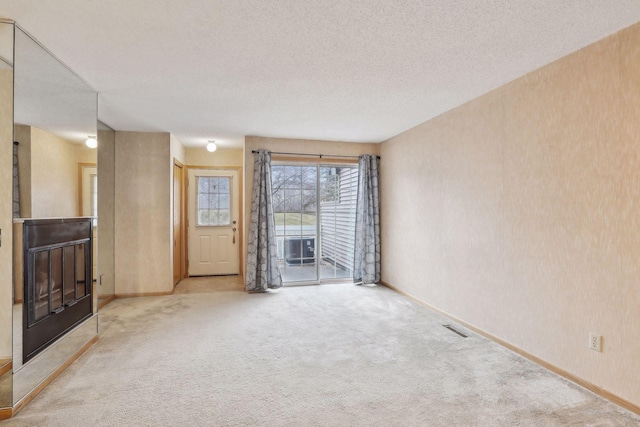 unfurnished living room featuring a textured ceiling and light colored carpet