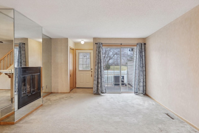 unfurnished living room with light carpet and a textured ceiling