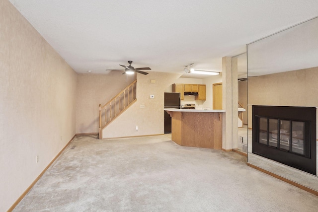 unfurnished living room featuring ceiling fan and light colored carpet