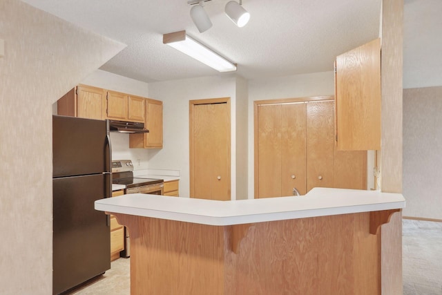 kitchen with stainless steel electric stove, kitchen peninsula, black refrigerator, and a breakfast bar