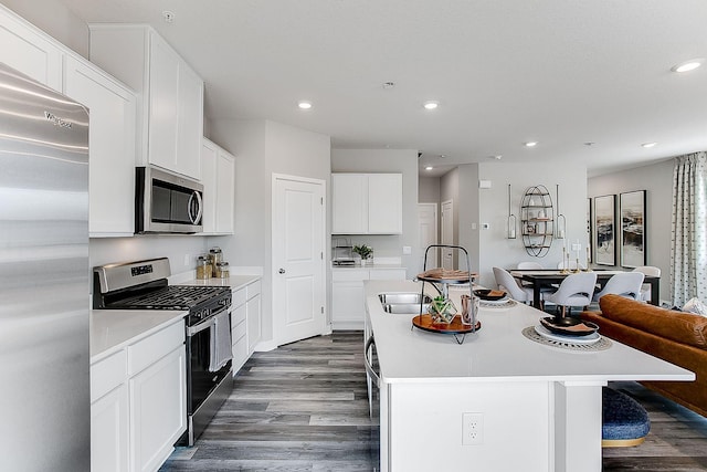 kitchen with a center island with sink, white cabinets, stainless steel appliances, and dark hardwood / wood-style floors