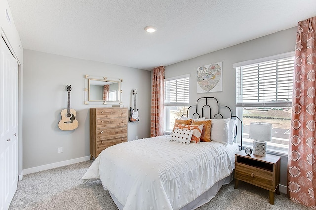 carpeted bedroom featuring multiple windows, a closet, and a textured ceiling