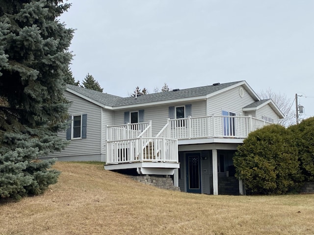 rear view of house featuring a wooden deck and a yard