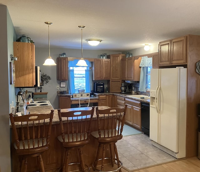 kitchen featuring a kitchen breakfast bar, sink, white refrigerator with ice dispenser, black dishwasher, and hanging light fixtures