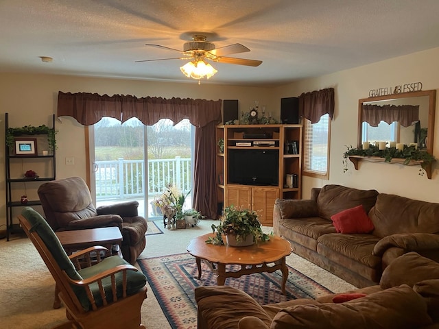 carpeted living room featuring ceiling fan and a textured ceiling