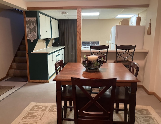 dining room with a paneled ceiling and concrete floors