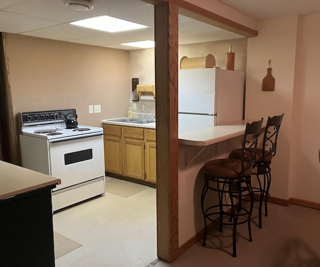 kitchen featuring a kitchen bar, sink, and white appliances