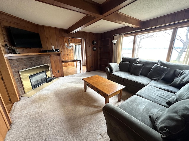 living room with wooden walls, beamed ceiling, light colored carpet, and a brick fireplace