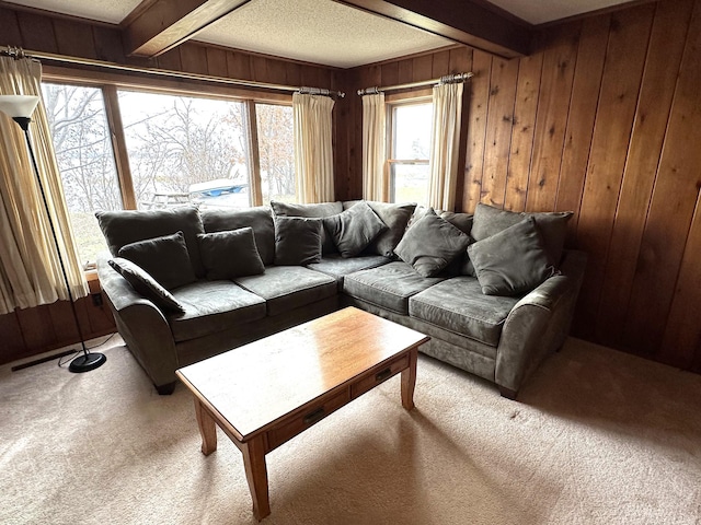 living room featuring light carpet, beam ceiling, a textured ceiling, and wooden walls