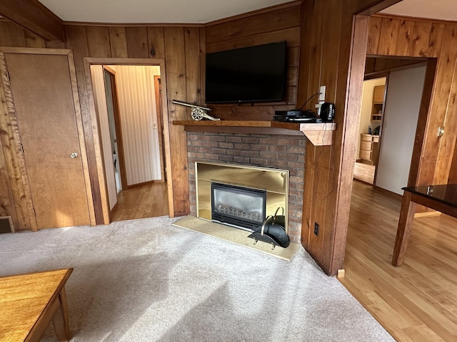 living room with a brick fireplace, wooden walls, and light hardwood / wood-style flooring