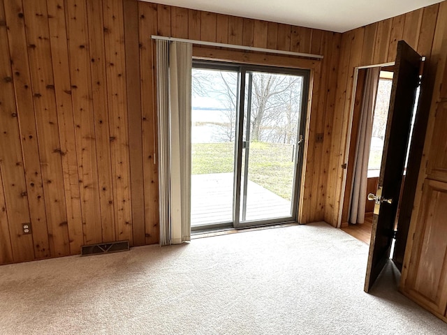 doorway to outside with carpet floors and wooden walls