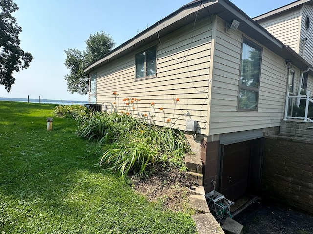 view of side of property featuring central air condition unit and a yard