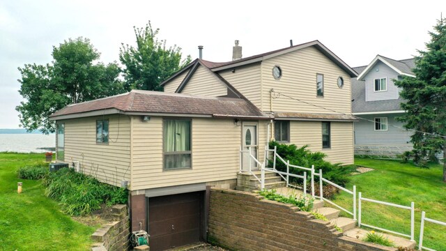 view of front of house featuring a chimney, a front lawn, and a garage