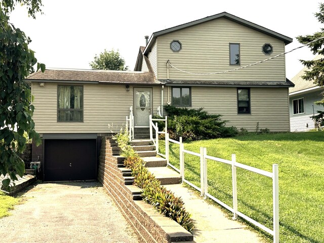 view of front facade featuring driveway, fence, a front yard, and a garage