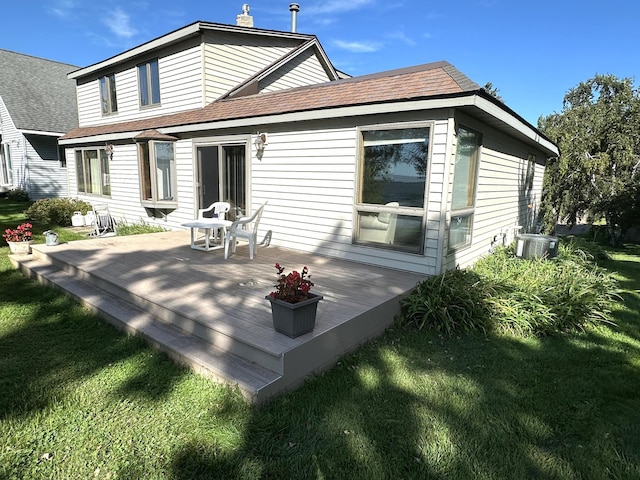 rear view of house with a lawn, a wooden deck, and a shingled roof