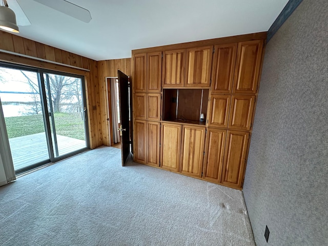 unfurnished living room with wooden walls and light carpet