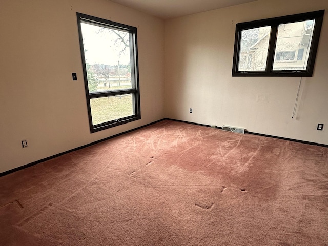 spare room featuring light colored carpet and baseboards