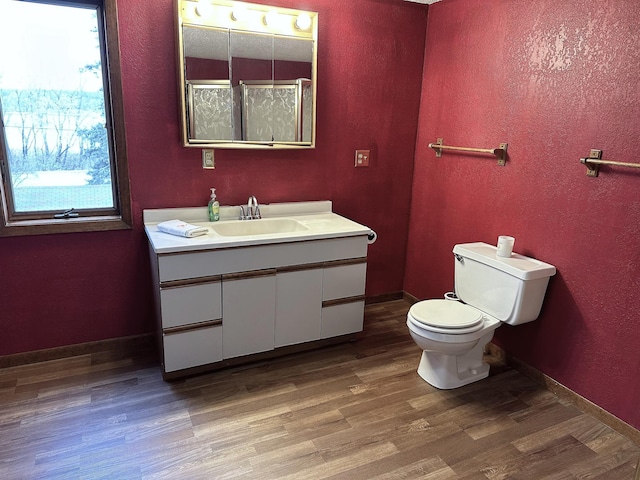 bathroom featuring vanity, toilet, a textured wall, baseboards, and wood finished floors