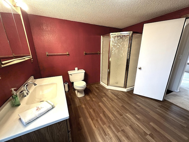 full bathroom with a textured ceiling, a stall shower, toilet, wood finished floors, and vanity