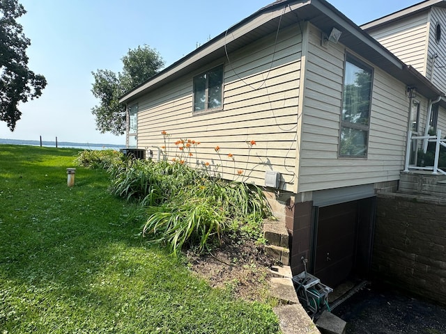 view of home's exterior featuring a garage, central air condition unit, and a lawn