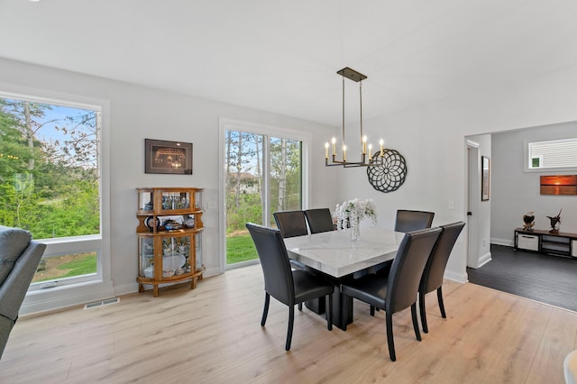 dining area with plenty of natural light, a chandelier, and light hardwood / wood-style flooring