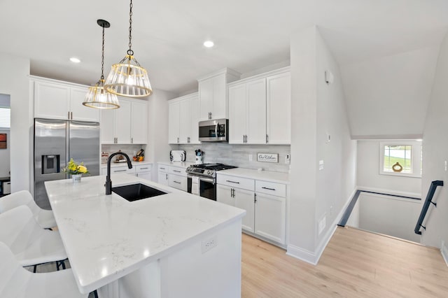 kitchen with white cabinetry, sink, hanging light fixtures, and appliances with stainless steel finishes