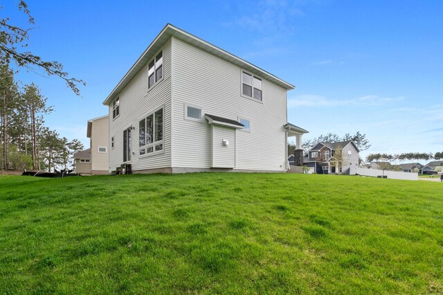 rear view of property featuring central AC and a lawn