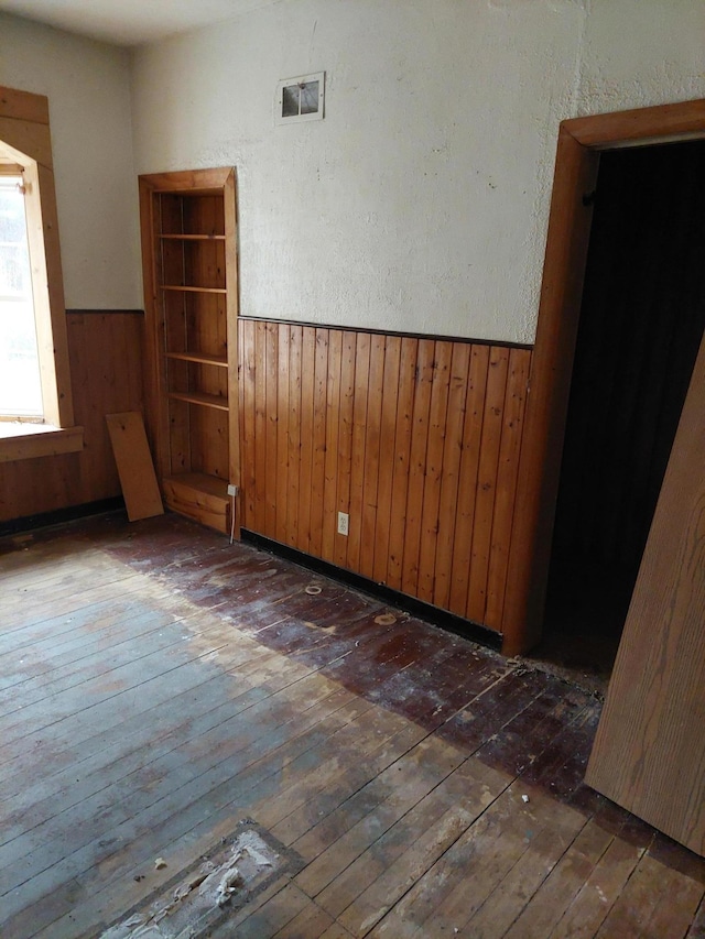 unfurnished room featuring dark wood-type flooring and wood walls