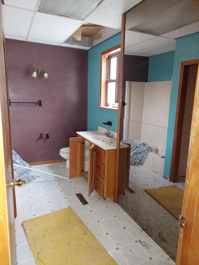 bathroom with a paneled ceiling, vanity, and toilet