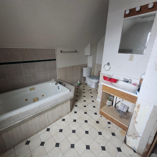 bathroom featuring tiled bath, vanity, and toilet