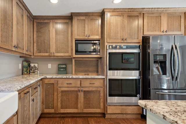 kitchen featuring stainless steel appliances, light stone counters, and dark hardwood / wood-style floors