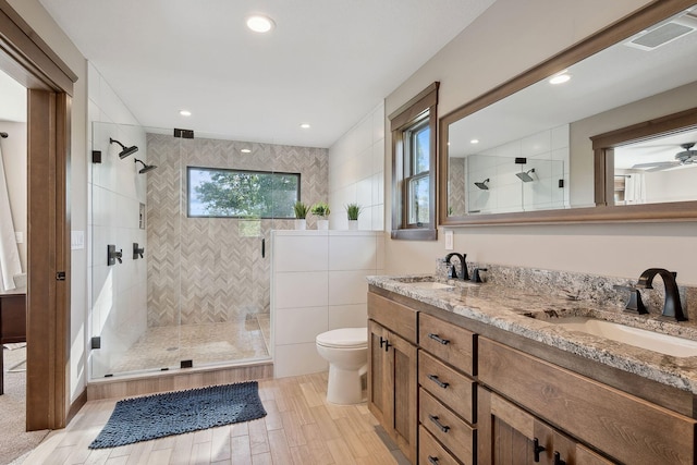 bathroom featuring toilet, tile walls, an enclosed shower, ceiling fan, and vanity