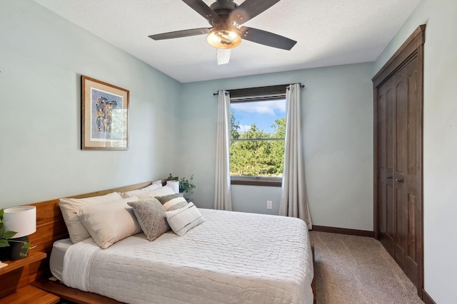 carpeted bedroom with a textured ceiling, ceiling fan, and a closet