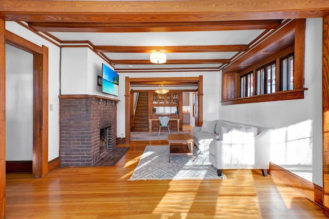 living room featuring a brick fireplace, hardwood / wood-style floors, a wealth of natural light, and an inviting chandelier