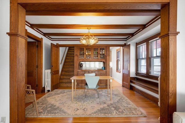 dining space with radiator heating unit, light wood-type flooring, and beam ceiling