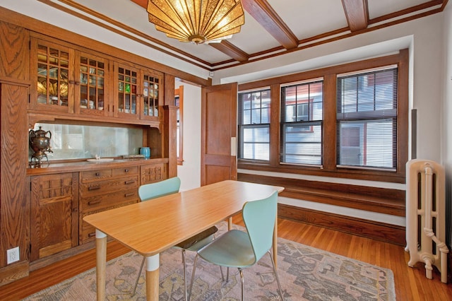 dining space featuring beam ceiling, light hardwood / wood-style floors, crown molding, and radiator