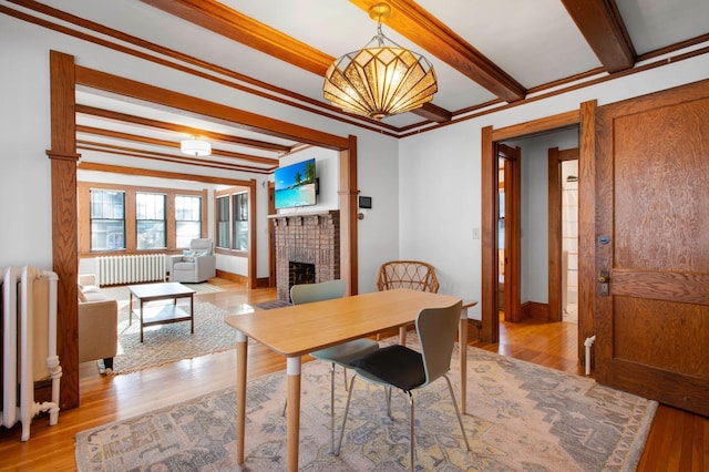 dining space featuring light hardwood / wood-style floors, radiator, and a brick fireplace