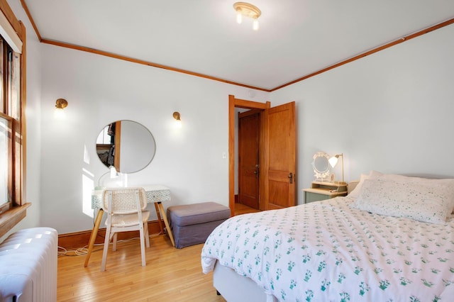 bedroom with light hardwood / wood-style floors, ornamental molding, and radiator